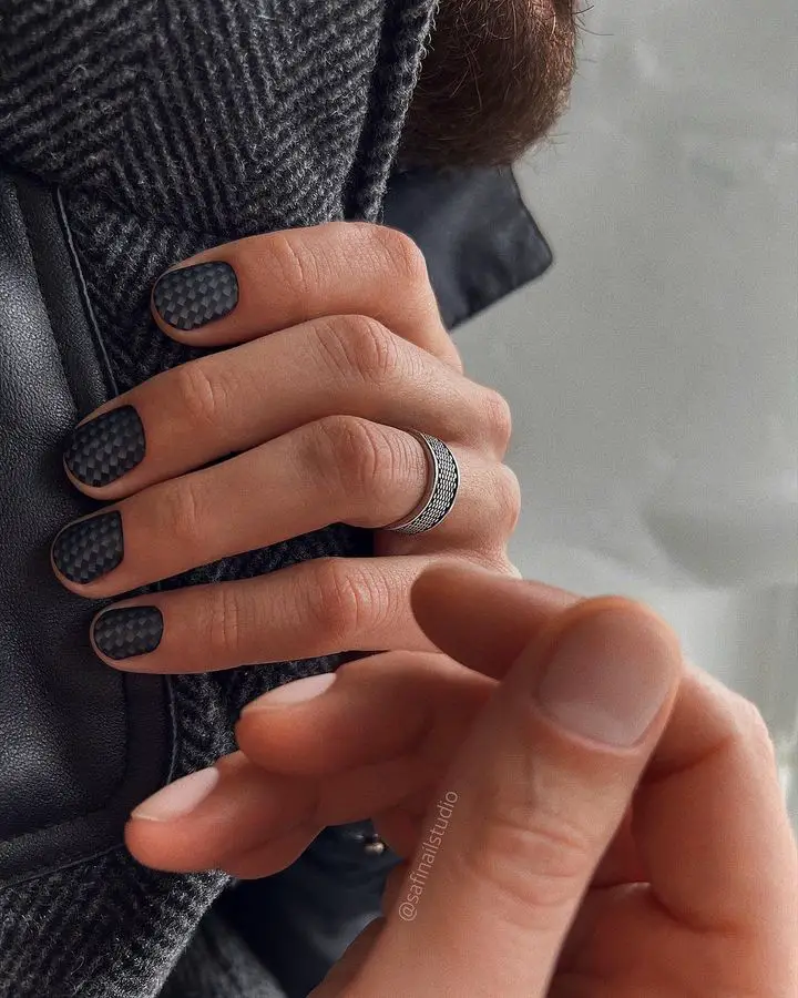 female hand with matte black nail with pattern 