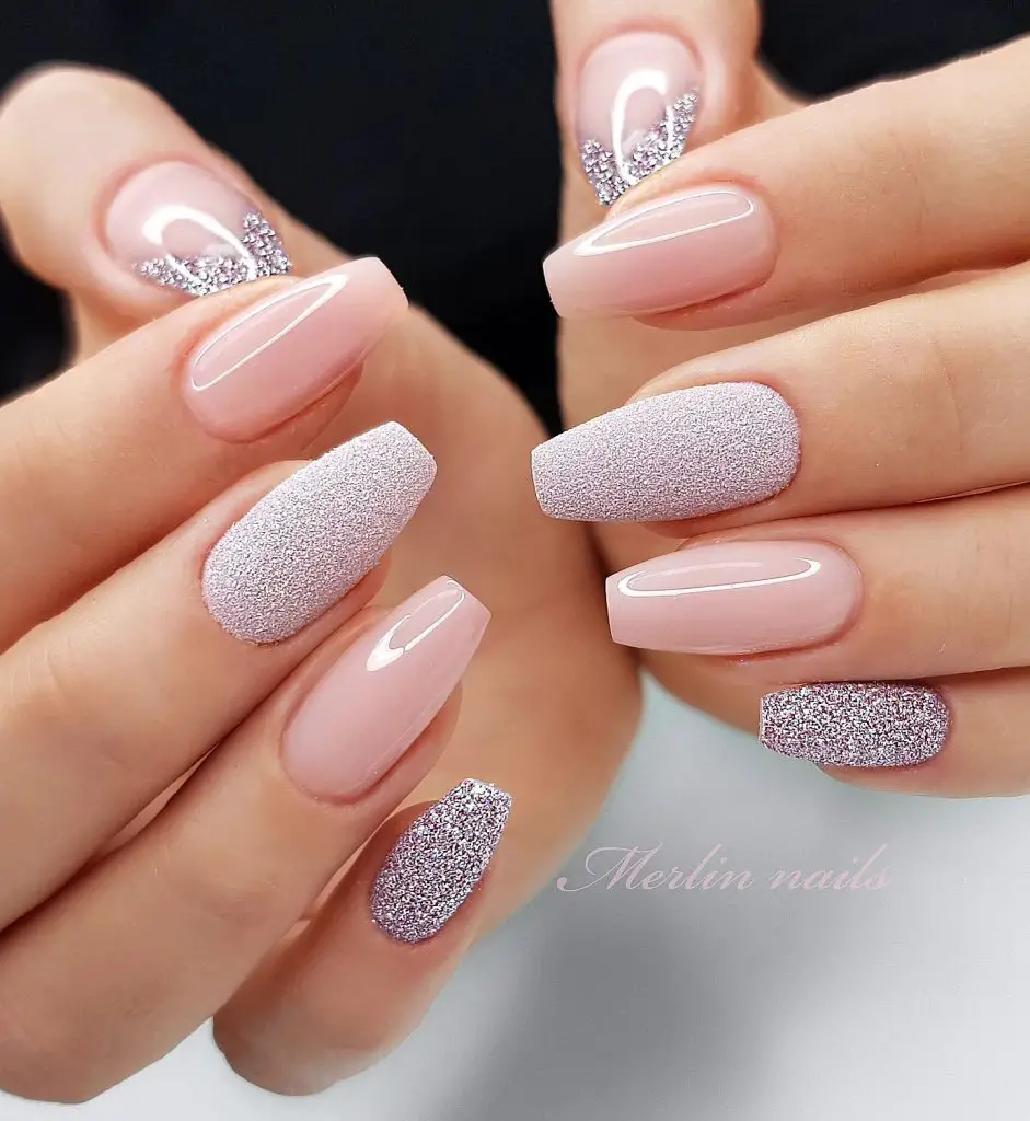 Alternating glossy and glitter-covered nails in a pale pink shade, showcasing a sparkling accent on the ring fingers and a simple white line design